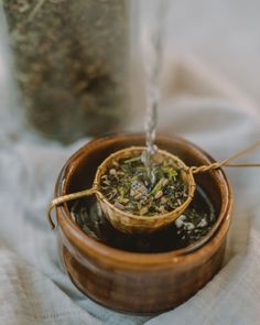 a wooden bowl filled with green tea on top of a table