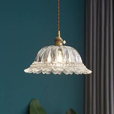 a glass light fixture hanging from a ceiling in a room with blue walls and curtains