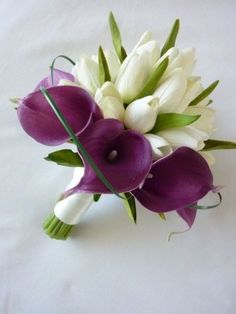 purple and white flowers are arranged in a bridal bouquet on a white sheeted surface