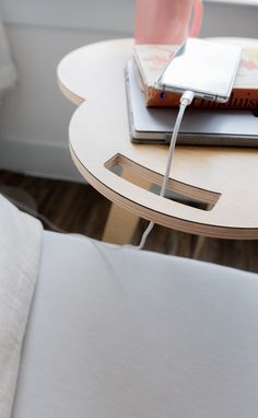 a laptop computer sitting on top of a wooden table next to a white chair and window