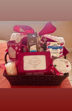 a red basket filled with lots of different items on top of a table next to a pink blanket