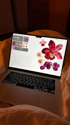 an open laptop computer sitting on top of a bed next to a comforter and pillows