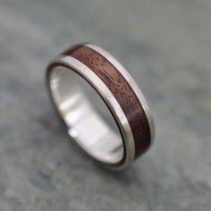 a wedding ring with wood inlays on the outside and inside, sitting on a concrete surface