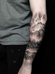 a man's arm with mountains and trees on it