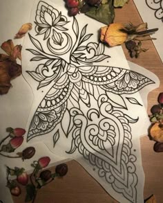 an intricately designed piece of paper with leaves and flowers on it, next to some scissors