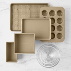 an assortment of baking pans and muffin trays on a marble countertop