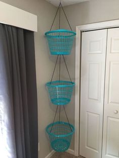 three blue baskets hanging from the ceiling in a room with a door and window behind them