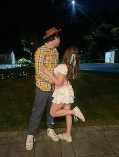 a young man and woman dancing on the sidewalk at night with headphones in their ears