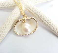 Beautiful gold sea shell necklace made with a gold plated seashell charm with a gold filled chain and fresh water pearl. This necklace makes a unique gift for a beach lover or someone special in your life. The seashell is around 15- 20mm long. Each item is carefully packaged in a beautiful jewellery box ready as a gift. If you would like to add a personalized note with your order, just write a note at checkout and I will send a small card with your gift to the recipient. Please choose necklace l Pearl Pendant Shell Gift, Pearl Pendant Shell As Gift, Handmade Gold Shell Strand, Handmade Gold Strand Shell, Yellow Gold Shell Necklace For Gift, Beach Jewelry With Pearl Pendant In Shell Shape, Shell-shaped Pearl Pendant Jewelry For Beach, Elegant Pearl Pendant Shell For Beach, Elegant Beach Pearl Shell Pendant