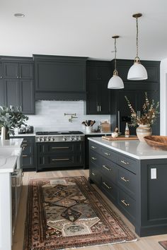 a kitchen with black cabinets and an area rug