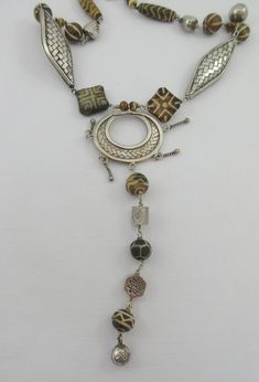 This is a fabulous sterling silver necklace with various ethnic tribal stone beads and large sterling silver woven beads. The central pendant is open and it has a long dangle attached to it. I believe the small beads are made out of bone. The beads are set in an almost symmetrical pattern starting from the central pendant and made out to resemble African necklaces. Probably artisan made. Very stylish and unique. The beauty of it all -- is the soft mellow chime that emanates from the round balls Handmade Artisan Silver Lariat Necklace, Artisan Handmade Silver Lariat Necklace, Artisan Sterling Silver Necklace For Festival, Adjustable Artisan Beaded Sterling Silver Necklace, Handmade Sterling Silver Beaded Necklaces For Festivals, Adjustable Artisan Sterling Silver Beaded Necklace, Handmade Sterling Silver Beaded Necklace For Festivals, Artisan Sterling Silver Adjustable Beaded Necklace, Unique Handmade Silver Lariat Necklace