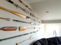 a living room filled with furniture and lots of different types of paddles on the wall