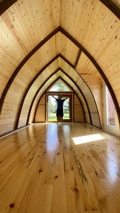 a person standing in an open room with wood floors