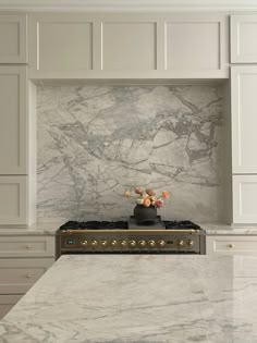 a stove top oven sitting inside of a kitchen next to white cupboards and drawers