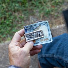 a man is holding a money bill in his left hand while another person sits on the ground behind him