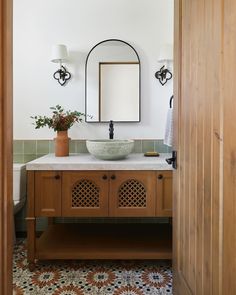 a bathroom with a sink, mirror and wooden cabinetry in it's center