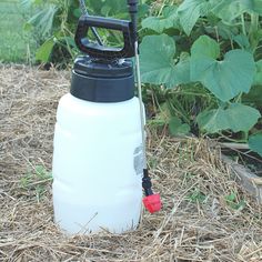 a white jug with a black handle and red spigot attached to it sitting in the grass