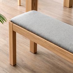 a wooden bench sitting on top of a hard wood floor next to a potted plant