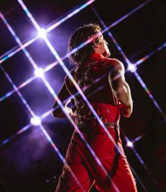 a male in a red shirt is dancing on stage