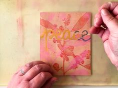 two hands holding up a piece of paper with the word peace on it and flowers