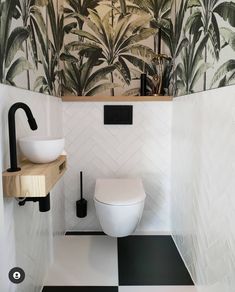 a white toilet sitting in a bathroom next to a wall mounted faucet and sink