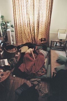 a messy room with clothes on the floor and a bed in front of a window