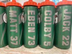 six green and orange sports bottles sitting on a counter