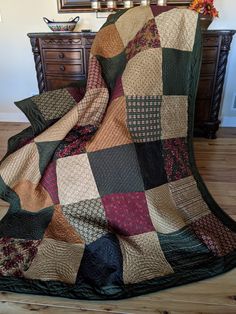 a quilted blanket sitting on top of a wooden floor next to a dresser and mirror