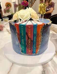 a cake decorated with books and flowers on a table