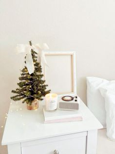 a small christmas tree sits on top of a white dresser next to a framed photo