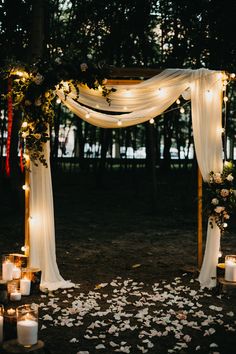 an outdoor ceremony with candles and flowers on the ground