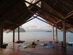 there are many yoga mats on the floor in front of the water with mountains in the background