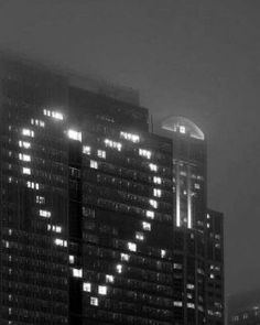 black and white photograph of buildings in the city at night with lights shining on them