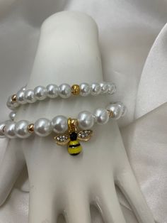 Sweet and stylish, my White and Gold Beaded Bee Charm Bracelet is the perfect accessory for any fashion-forward femme! Two strands of crisp white beads are accented with a delicate gold bee charm, adding a touch of elegance and whimsy to your wrist. Wear it alone or stacked with others for a look that's simply buzz-worthy! Bee Bracelet, Bracelet Inspo, Wrist Accessories, Gold Bee, Wrist Wear, Bee Charms, Tie Styles, White Beads, Charm Bracelets