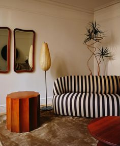 a black and white striped couch sitting in a living room next to two mirrors on the wall