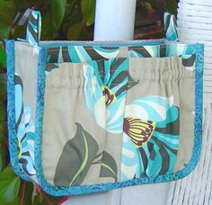 a purse hanging on the side of a white fence with blue and green flowers in it