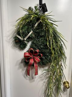 a christmas wreath hanging on the wall next to a pair of scissors and a bow