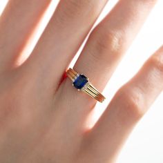 a woman's hand with a gold and blue ring on top of her finger