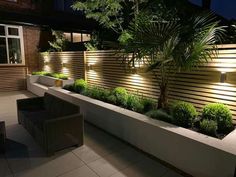 an outdoor area with plants and lights on the wall, along with wicker furniture