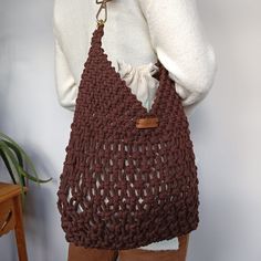 a woman holding a brown crocheted purse