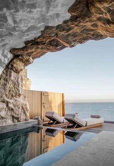 an outdoor swimming pool with chaise lounges next to the ocean