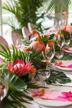 the table is set with pink flamingos and tropical leaves for an elegant dinner party