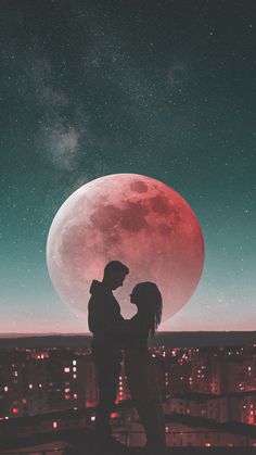 two people standing in front of a full moon