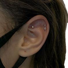 a woman's left ear with three small diamond studs on the top of it