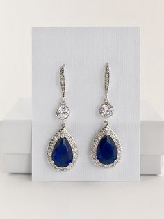 Luxury blue sapphire cubic zirconia bridal tear drop earrings in rhodium plated brass setting. Earrings feature a large teardrop with pear cut blue sapphire cubic zirconia center surrounded by tiny round zirconia crystals. Teardrop dangles from a round cubic zirconia connector and zirconia detailed ear wire. Total length of the earrings is 5 cms. For matching necklace click: https://www.etsy.com/listing/252983612/blue-sapphire-cubic-zirconia-bridal?ref=shop_home_active_13 For matching bracelet c Blue Sapphire Pear-shaped Earrings, Elegant Blue Drop Crystal Earrings, Sapphire Dangle Crystal Earrings For Formal Occasions, Sapphire Crystal Drop Earrings For Formal Occasions, Sapphire Crystal Dangle Earrings For Formal Events, Sapphire Crystal Dangle Earrings For Formal Occasions, Blue Elegant Teardrop Pendant Earrings, Elegant Blue Teardrop Earrings, Blue Elegant Teardrop Earrings