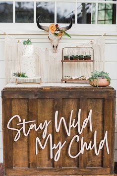 a wooden sign that says stay wild my child on top of a table with flowers