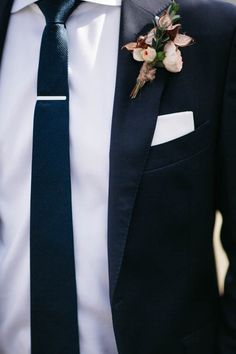 a man wearing a suit and tie with flowers on it's lapel pin