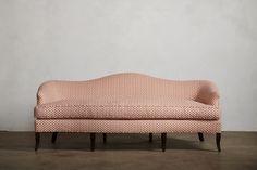 an upholstered couch sitting on top of a wooden floor next to a wall