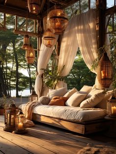 a bed sitting on top of a wooden floor covered in pillows and blankets next to lanterns