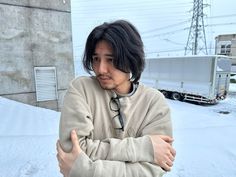 a man with his arms crossed standing in front of a snow covered building and power lines